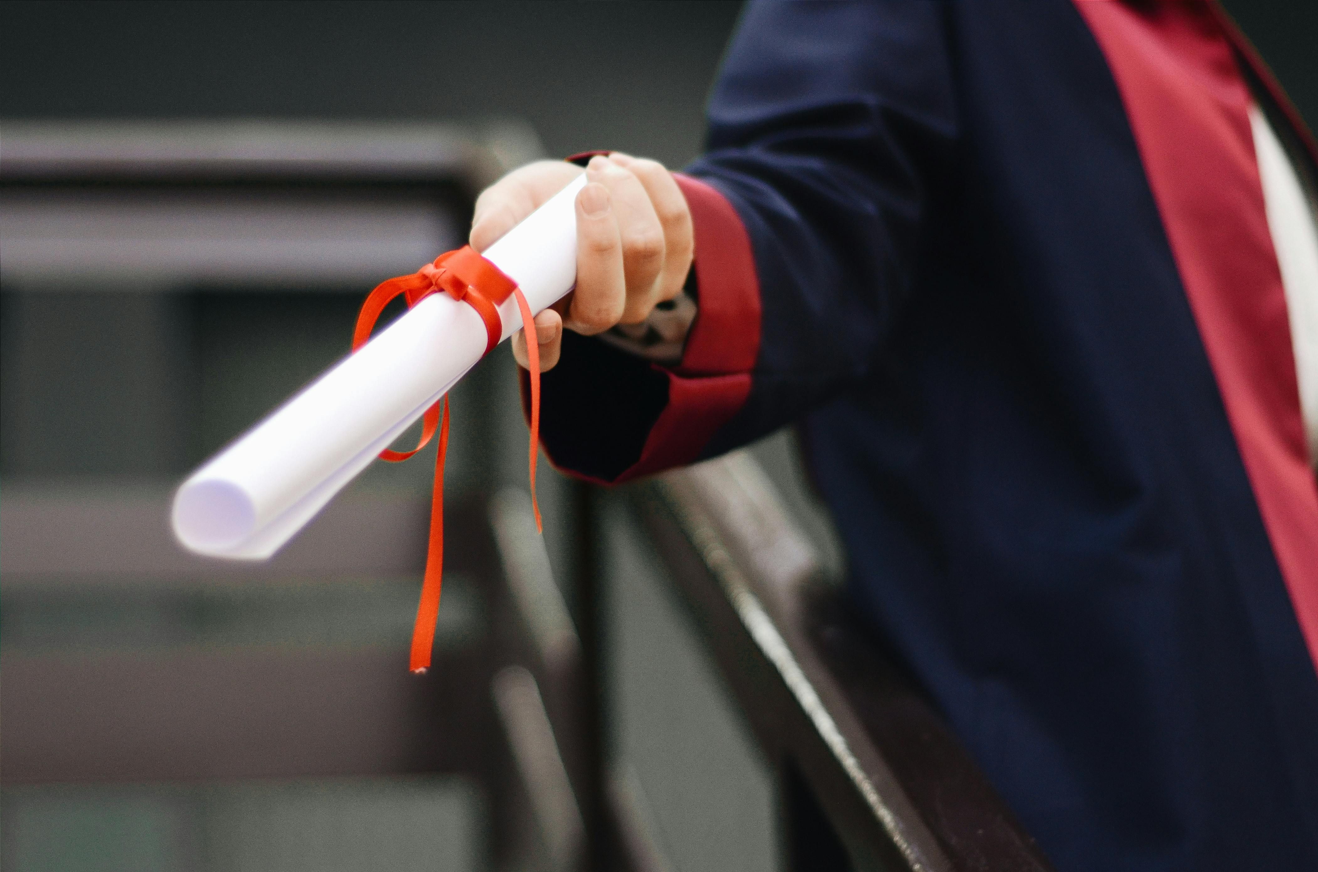 Jeune diplômé tenant son diplôme le jour de la remise des diplômes